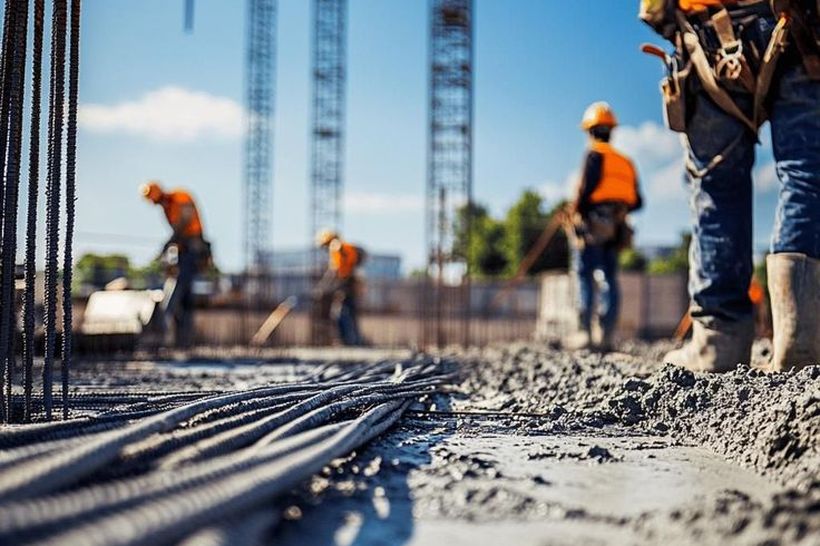 Trabajadores de la construcción en obra junto a varillas de acero