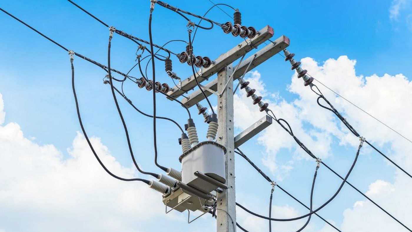 Poste de distribución eléctrica con transformador y cableado contra un cielo azul